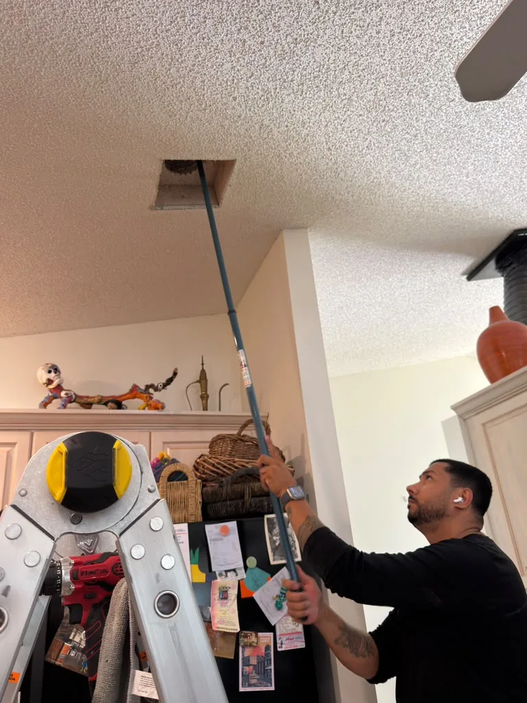HVAC Solution technician cleaning vent with tools and ladder